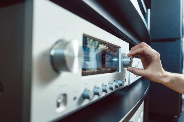 Hand of woman turning up volume of Hi-Fi amplifier in her home